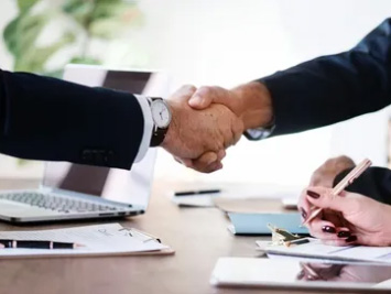 Business partners shaking hands across a meeting table